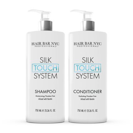 Two 750 ml white pump bottles labeled “Silk Touch System Duo Bundle” stand side by side—shampoo on the left, conditioner on the right. Both are paraben-free, keratin-infused, and feature a minimalist design with black and blue text.