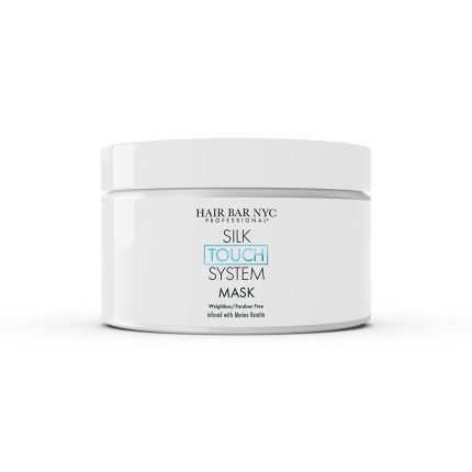 A white plastic jar labeled "Silk Touch System Mask" features nano keratin and a weightless, paraben-free formula. Its clean, minimal design stands out against the white background.