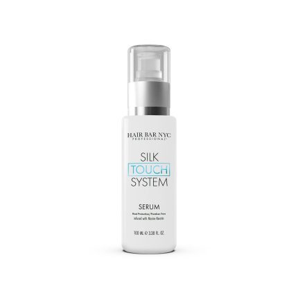 A white bottle of Silk Touch System Serum with a clear cap and pump dispenser. The label shows black and blue text, states 100 ml (3.38 fl oz), and highlights it as a professional hair product infused with keratin.